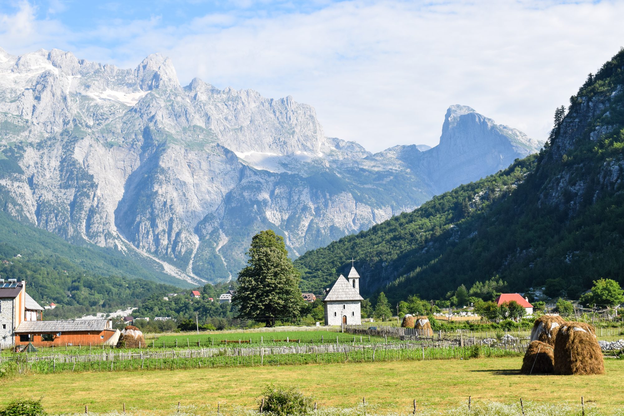 The stone-built Church of Theth in the valley, surrounded by meadows and limestone peaks.