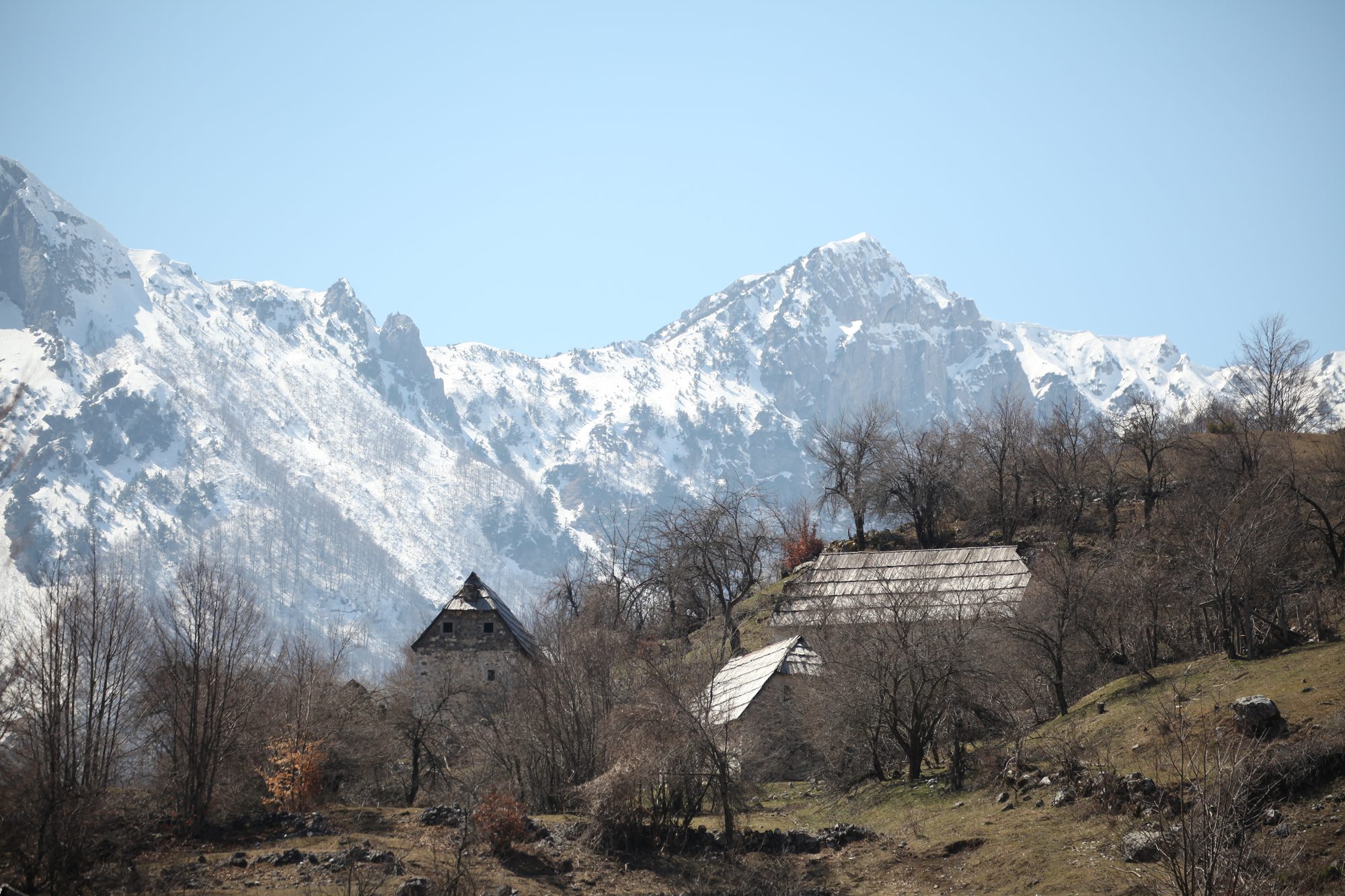 The Valbona valley in northern Albania, a broad green river valley ringed by steep grey limestone peaks.