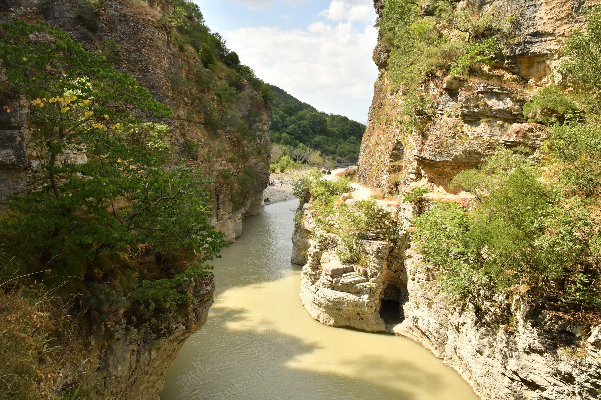 The Osumi river running green between sheer layered limestone walls at the mouth of the canyon.